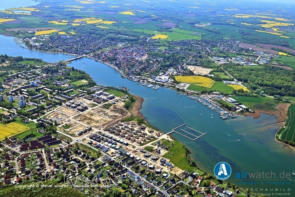 Luftbild Kappeln an der Schlei & Ellenberg | Im Norden des Stadtteils Ellenberg befindet sich der Wanderpfad „Holzweg“, der durch ein Wäldchen zu einem Aussichtspunkt direkt an der Schlei führt und eine kleine Landzunge bietet, die sich in die Schlei erstreckt. Dieser Ort eignet sich gut für Picknicks mit Blick auf Maasholm, Schleimünde und das Ostsee Resort Olpenitz. An der Haltestelle Ellenberg/Schleibrücke in Kappeln fahren Buslinien wie die Linie 1 und die Linie 712 ab.