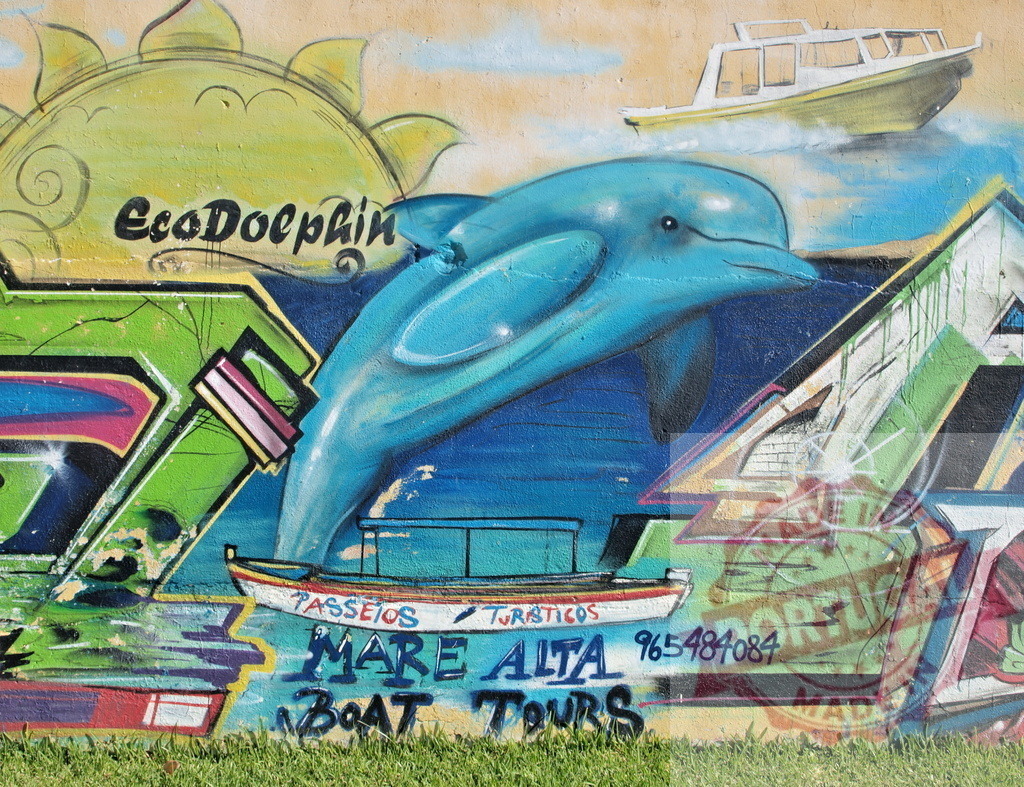 Colorful dolphin jumping in eco dolphin graffiti art with boats and sun | Graffiti art featuring a dolphin jumping out of the water, with boats, a sun, and the words EcoDolphin and Mare Alta Boat Tours - Realized with Pictrs.com