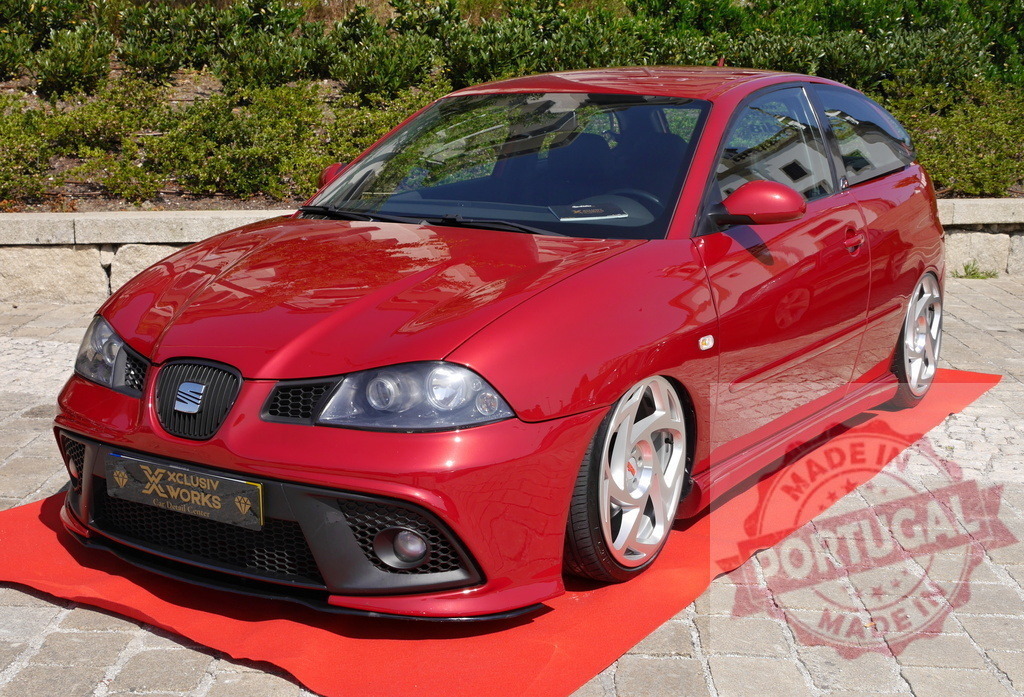 Red modified Seat Ibiza on red carpet at car show | Custom red Seat Ibiza hatchback showcasing tuning and low rider suspension on a red carpet outdoors - Realisiert mit Pictrs.com