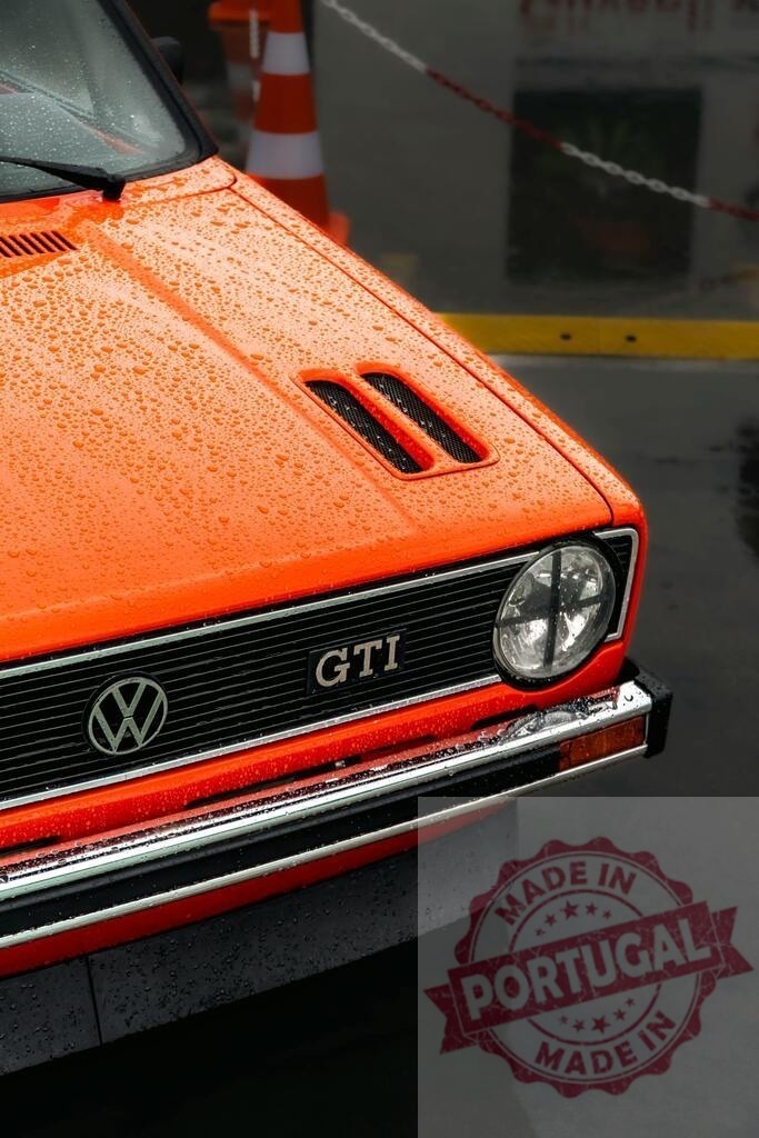 Volkswagen Golf GTI classic car with rain droplets | Orange Volkswagen Golf GTI parked during rain, showing hood, grille, and headlight - Realisiert mit Pictrs.com