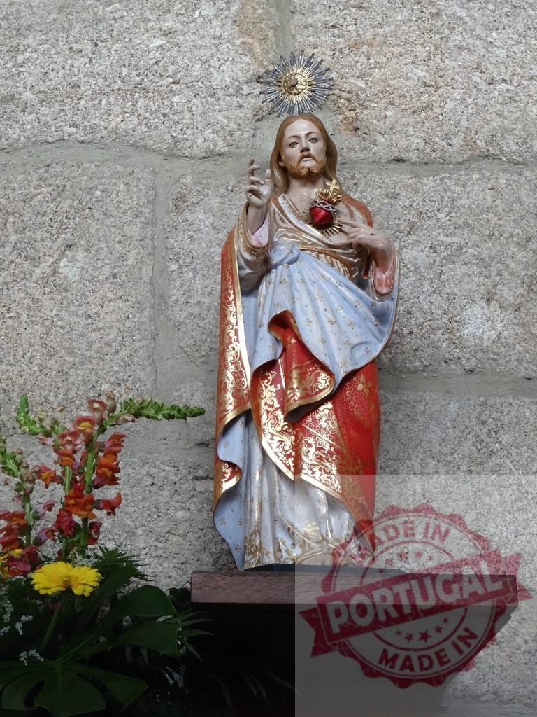 Sacred Heart of Jesus statue with floral decoration | Sacred Heart of Jesus statue standing on a wooden pedestal with flowers - Realisiert mit Pictrs.com