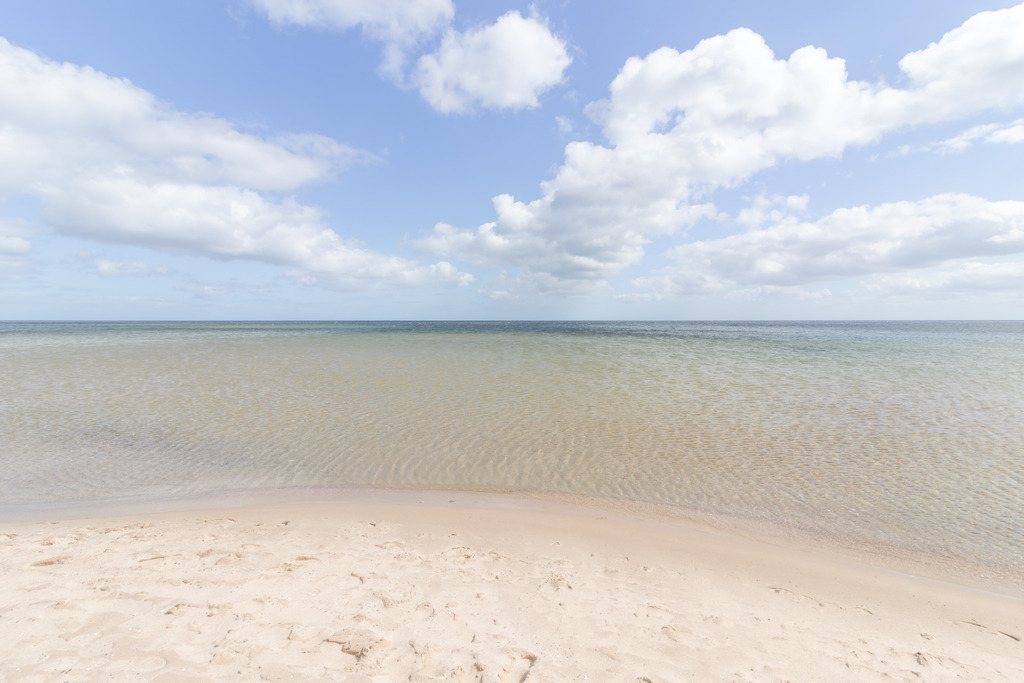 Wandbild: Weite am Weidefelder Strand | Der Weidefelder Strand bei Kappeln zeigt sich hier in seiner stillen, offenen Weite: heller Sand, sanftes Küstenwasser und ein Himmel, der sich mit leichten Wolken über die Ostsee spannt. Die klare Horizontlinie und das ruhige Farbspiel zwischen Sand, Meer und Himmel schaffen eine Atmosphäre, die Gelassenheit und Leichtigkeit ausstrahlt. Als Wandbild bringt diese Szene die helle, natürliche Ruhe der Kappelner Küste in den Raum und öffnet ihn für einen Moment von Weite und maritimer Klarheit.