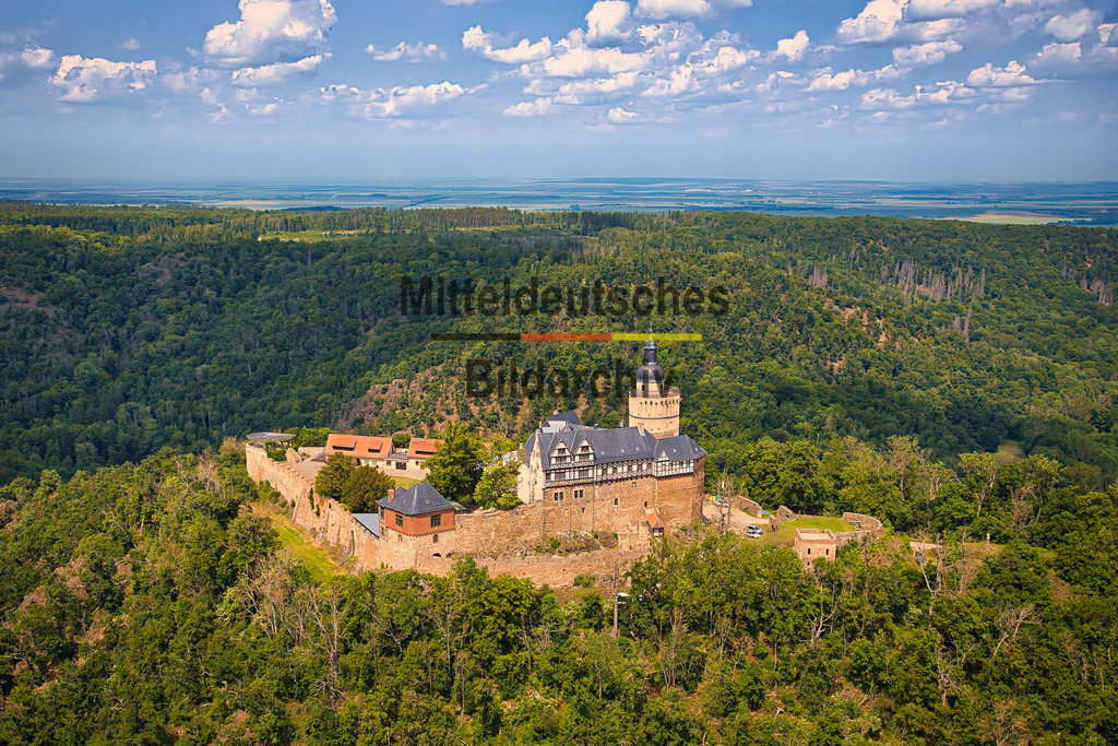 Burg_Falkenstein_5067 | Dieses Luftbild zeigt die Burg Falkenstein im Harz in Sachsen-Anhalt aus der Perspektive eines Tragschraubers. Die mittelalterliche Burganlage erhebt sich auf einem bewaldeten Bergrücken und gehört zu den bekanntesten und besterhaltenen Burgen des Harzes. Aus der Luft wird besonders deutlich, wie eindrucksvoll die Burg in die ausgedehnten Waldlandschaften des Naturparks Harz eingebettet ist.Die Geschichte der Burg Falkenstein reicht bis in das 12. Jahrhundert zurück. Über Jahrhunderte hinweg war sie ein bedeutender Herrschaftssitz und zählt heute zu den wichtigsten Kulturdenkmalen Sachsen-Anhalts. Die markanten Mauern, Türme und Gebäude sind weithin sichtbar und bilden einen reizvollen Kontrast zur umgebenden Natur.Besonders beeindruckend ist die Weite der Waldlandschaft, die einen großen Teil der Aufnahme prägt. Dichte Laub- und Nadelwälder erstrecken sich bis zum Horizont und verdeutlichen die einzigartige Lage der Burg mitten im Harz. Aus der Vogelperspektive wirkt die Anlage wie eine Insel aus Stein in einem Meer aus Grün.Dieses Luftbild verbindet die historische Architektur der Burg Falkenstein mit der beeindruckenden Natur des Harzes und zeigt eines der schönsten Ausflugsziele Sachsen-Anhalts aus einer außergewöhnlichen Perspektive. - Realisiert mit Pictrs.com