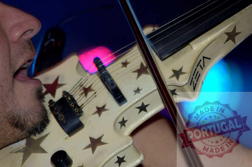 Musician singing and playing Zeta electric violin with star decorations during live performance | Close-up of a musician singing and playing a decorated Zeta electric violin during a concert with colorful stage lights - Realisiert mit Pictrs.com