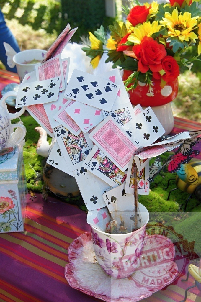 Alice in Wonderland themed tea party with playing cards | Playing cards overflowing from a teacup at a whimsical outdoor Alice in Wonderland tea party - Realized with Pictrs.com