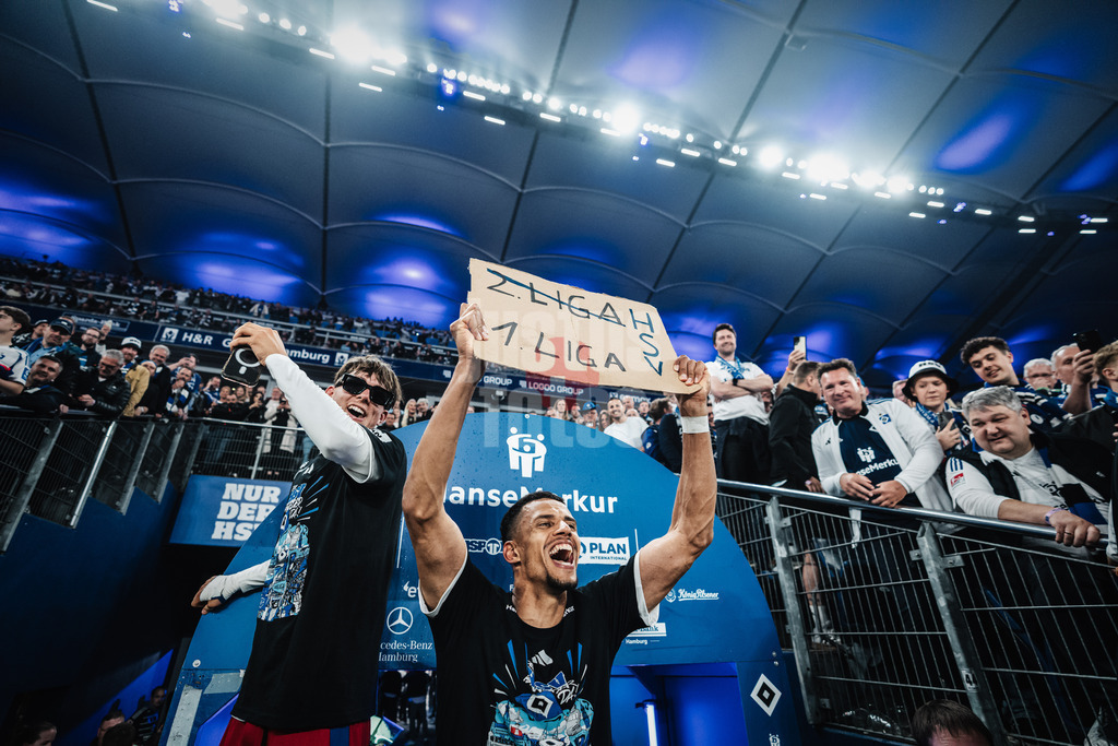 Fußball | Männer | Saison 2024/2025 | 2. Fußball-Bundesliga | 33. Spieltag | Hamburger SV vs. SSV Ulm 1846 | 10.05.2025 | v.l. Otto Emerson Stange (#49, HSV) und Robert Glatzel (#9, HSV) feiern den Aufstieg mit einem Schild 2 Liga durchgestrichen 1 Liga HSV