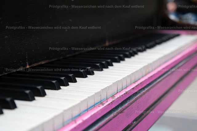 Tasten eines alten Klaviers | Detailaufnahme eines alten Klaviers mit flacher Perspektive entlang der Tasten. Die geringe Schärfentiefe, die dunkle Oberfläche und der farbige Akzent erzeugen eine ruhige, musikalische und leicht nostalgische Stimmung. - Realisiert mit Pictrs.com