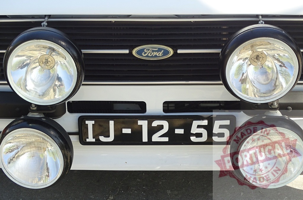 Ford Escort rally car driving lights and license plate | Front detail of an old Ford Escort rally car showing auxiliary lights and grille - Realized with Pictrs.com