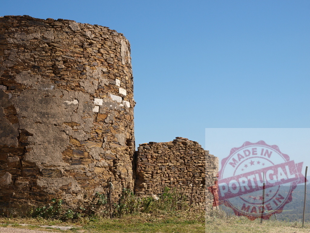 Ancient stone tower ruin against blue sky in countryside | Old stone tower ruin standing on a hill overlooking a rural landscape - Realisiert mit Pictrs.com