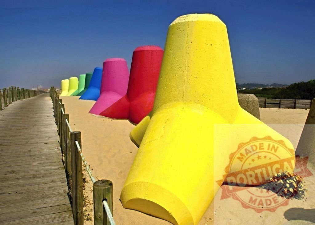 Aveiro Region - Portugal Colorful tetrapods protecting a sandy beach shoreline | Vibrant concrete tetrapods lining a beach next to a wooden boardwalk under blue sky - Realized with Pictrs.com