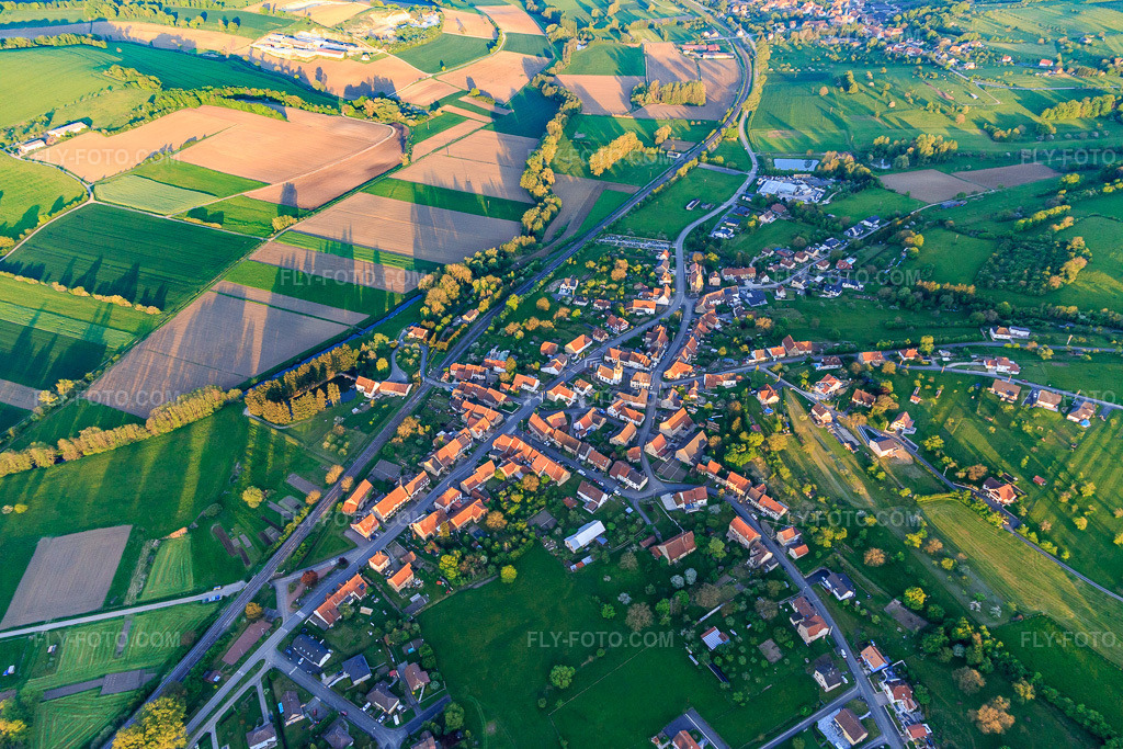 Aerial view: Village overview in the evening from the northwest in Vœllerdingen in the state Bas-Rhin, France. – Photo: IMG_145883.jpg taken on 04/30/2025 by Werner Riehm/FLY-FOTO.com – Resolution of the original: 5472 x 3648 px
