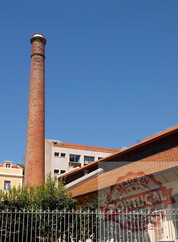 Old brick chimney standing tall against blue sky | Tall brick chimney rising above urban buildings and rooftops on a clear day - Realisiert mit Pictrs.com