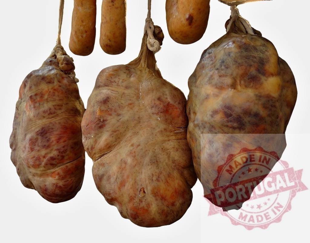 Three large dry-cured pork charcuterie hanging traditional way | Three large dry-cured pork charcuterie items hanging against a white background - Realized with Pictrs.com