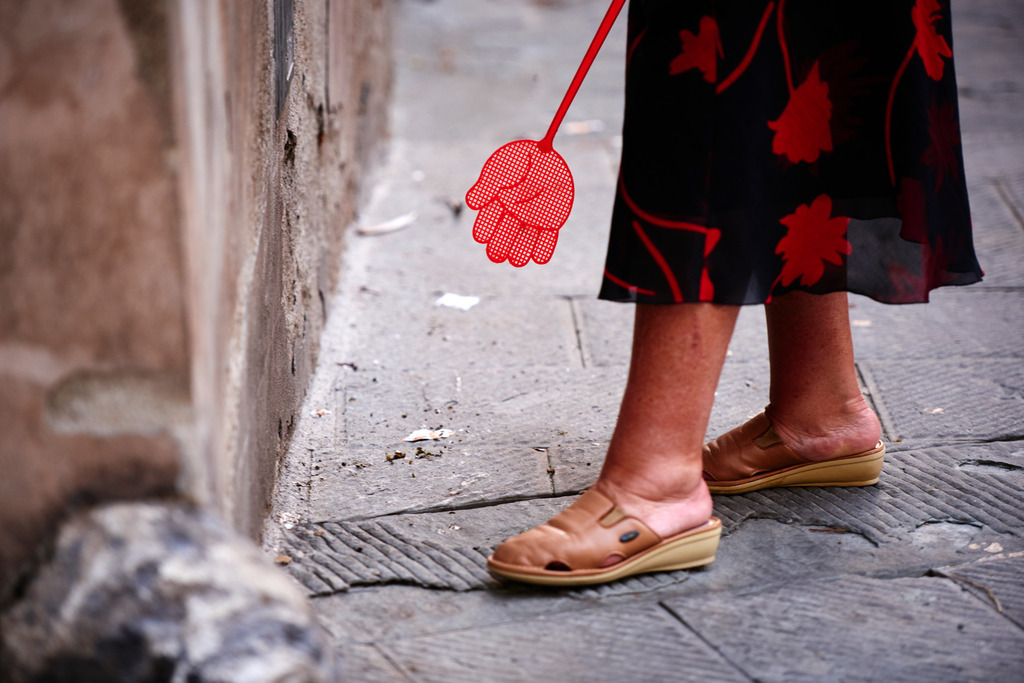 Frau mit roter Fliegenklatsche in der Hand | Asciano, Italien - September 01, 2016: Frau mit roter Fliegenklatsche in der Hand. - Realisiert mit Pictrs.com