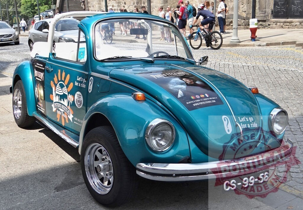 Turquoise Volkswagen Beetle parked on cobblestone street showcasing travel advertisement | Classic turquoise Volkswagen Beetle parked, displaying travel-related advertisements, evoking feelings of adventure and wanderlust - Realisiert mit Pictrs.com