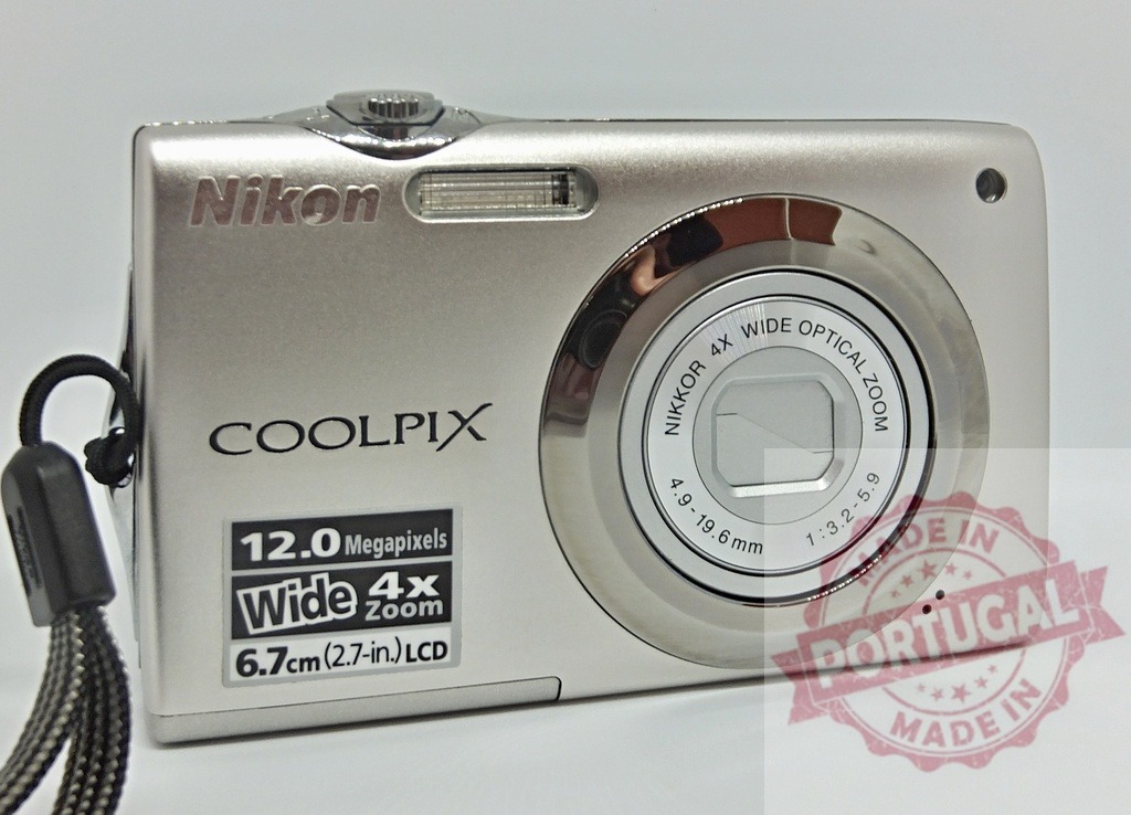 Nikon Coolpix digital compact camera providing technology | Nikon Coolpix digital camera showcasing its silver body and lens on white background - Realized with Pictrs.com