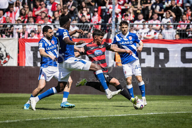 German 3rd Division, Viktoria Koeln vs. Energie Cottbus, 26.04.2026 | KOELN, GERMANY - APRIL 26, 2026:  Taylan Duman (FC Viktoria Koeln, 4) tackled by Tolcay Cigerci (Energie Cottbus, 10), King Manu (Energie Cottbus, 2) and Simon Straudi (Energie Cottbus, 44) during the 3rd division match on gameday 35 between Viktoria Koeln vs. Energie Cottbus at the Sportpark Hoehenberg on April 26, 2026 in Koeln, Germany. DFL REGULATIONS PROHIBIT ANY USE OF PHOTOGRAPHS AS IMAGE SEQUENCES AND/OR QUASI-VIDEO.