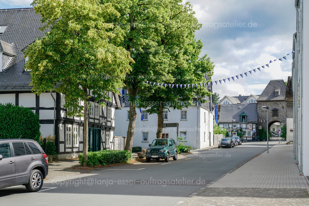 Derkerer Straße und Derkerer Tor in Brilon | Derkere Straße in Brilon mit Blick auf das Derker Tor. Schützenfest, Wimpel und Fahnen schmücken die Stadt. Sommertag mit blauem Himmel