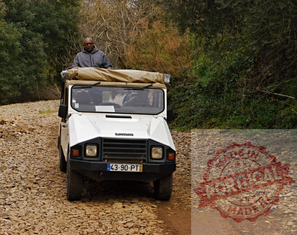 Man standing in off-road safari vehicle in Portugal | Man enjoying an adventure safari tour in a UMM Alter II 4x4 vehicle on a rocky road - Realized with Pictrs.com