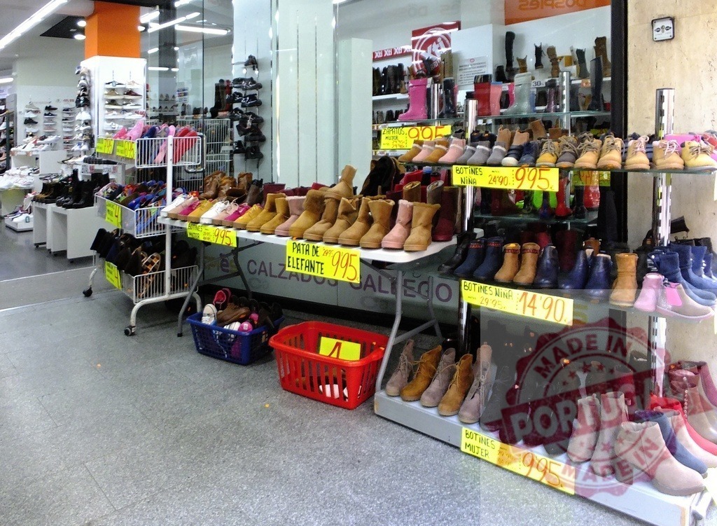 Shoe store displaying footwear selection with price tags | Retail shoes and boots are for sale on shelves and tables at a Calzados Gallego shop - Realisiert mit Pictrs.com