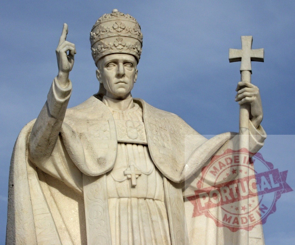 Statue of Pope John Paul II raising his right index finger and holding a cross | Marble statue of Pope John Paul II holding a cross and raising his right index finger against a blue sky - Realized with Pictrs.com