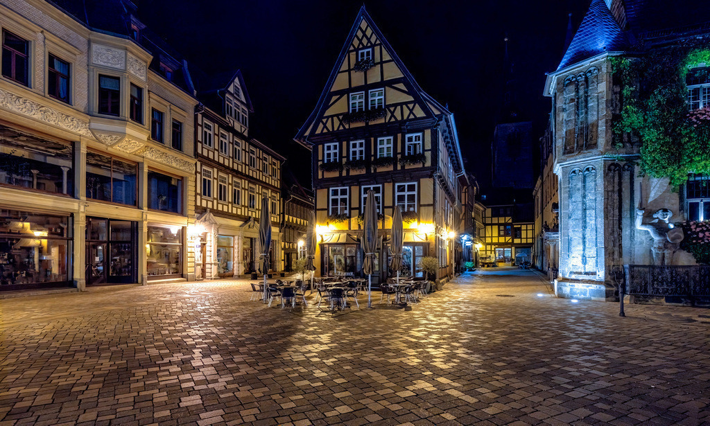 Der Marktplatz in Quedlinburg bei Nacht | Das Bild zeigt eine nächtliche Aufnahme des Marktplatzes in Quedlinburg, Sachsen-Anhalt. Ort: Die historische Altstadt von Quedlinburg, bekannt für ihre gut erhaltenen Fachwerkhäuser.Architektur: Im Zentrum ist ein markantes Fachwerkhaus zu sehen, typisch für die Region.Stimmung: Die Aufnahme fängt eine ruhige nächtliche Atmosphäre auf dem gepflasterten Platz ein.Bedeutung: Quedlinburg ist UNESCO-Weltkulturerbe und war Drehort für verschiedene Filmproduktionen. - Realisiert mit Pictrs.com
