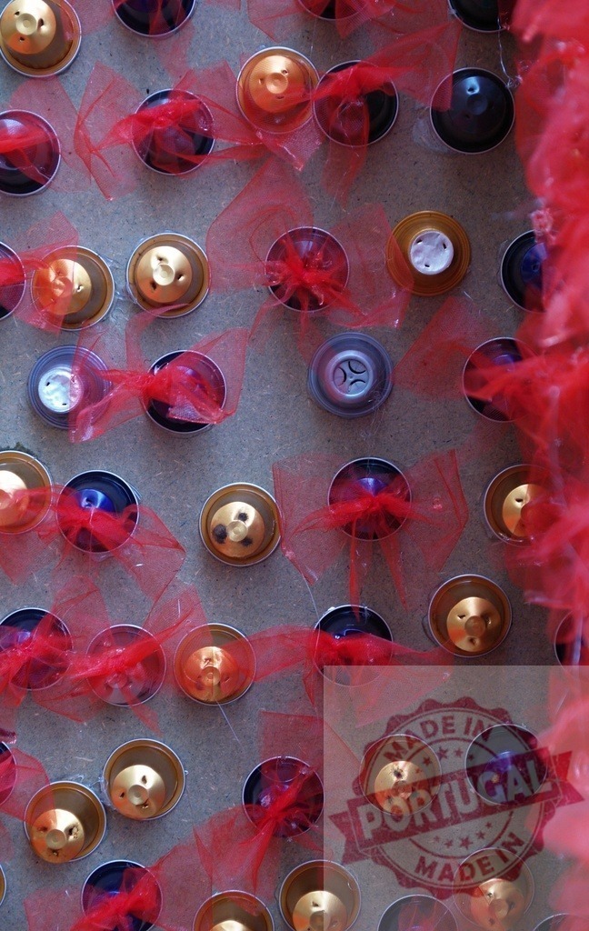 Coffee capsules arranged on a board, decorated with red ribbons, creating an abstract pattern | Coffee capsules arranged on a board, decorated with red ribbons, forming an abstract pattern, ideal for backgrounds or textures - Realisiert mit Pictrs.com