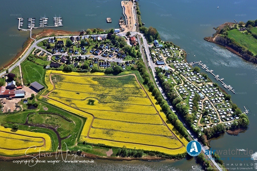 Luftbild Ostseefjord Schlei, Lindaunisbrücke, Landschaftsschutzgebiet Schwansener Schleilandschaft | In Lindaunis befindet sich die Lindaunisbrücke, eine Klappbrücke in Stahlgitter-Kastenkonstruktion für den Eisenbahn- und Straßenverkehr. Diese ist im Moment aber im Umbau. Da ein Teil der Brücke bereits abgerissen wurde, ist die Fahrt mit der Bahn zurzeit nicht möglich. Der Bahnhof Lindaunis wurde 1987 geschlossen und das Empfangsgebäude danach als Gaststätte genutzt. 2021 wurde der Bahnsteig wieder aufgebaut und zunächst für den touristischen Verkehr zwischen Kappeln und Eckernförde reaktivier
