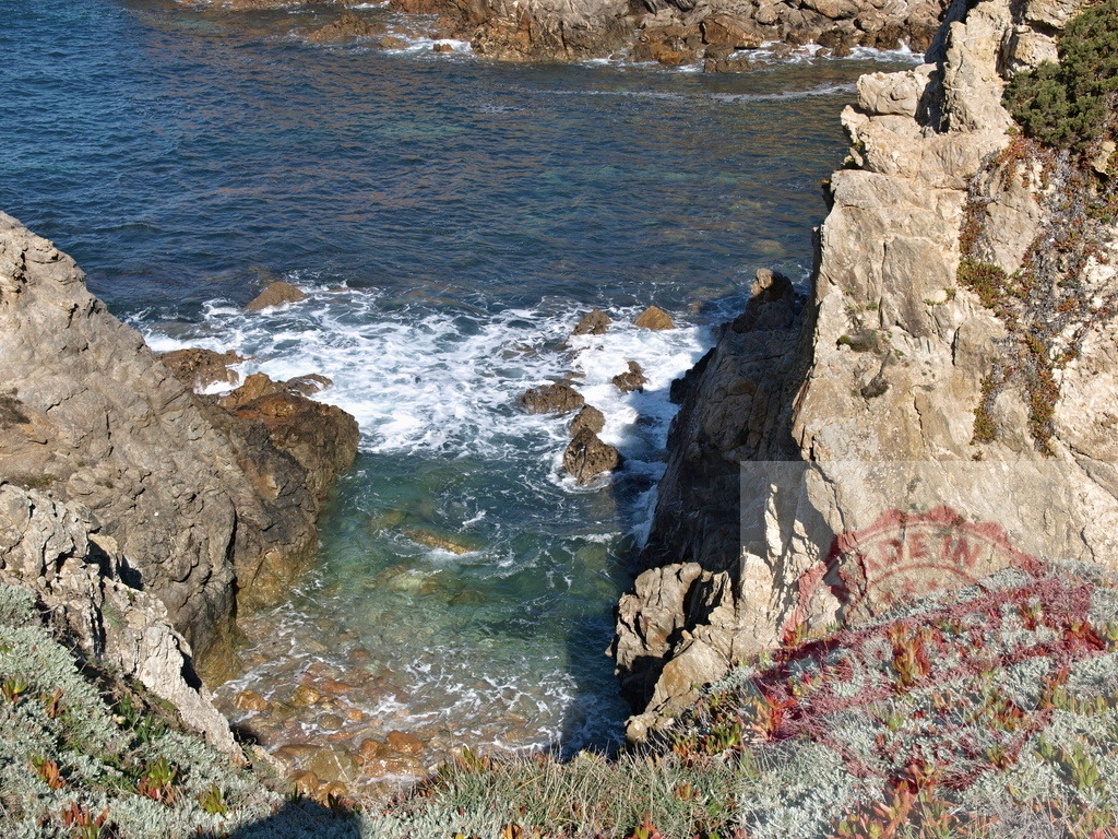 Rocky coast with waves creating foam on water | Ocean waves breaking on brown rocks along a rugged coastline - Realisiert mit Pictrs.com