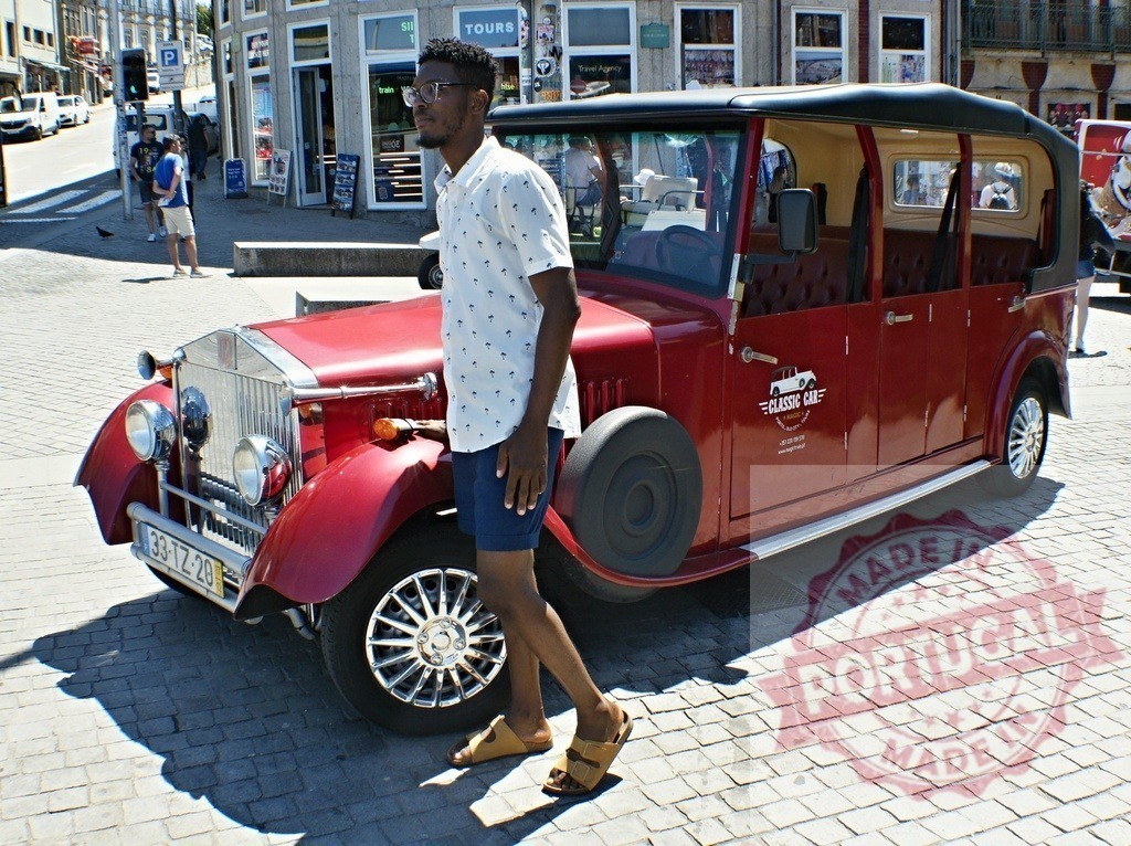 Young black man walking past classic red tour car in Porto | Young man exploring a city street with a vintage tourist car on a sunny day - Realisiert mit Pictrs.com