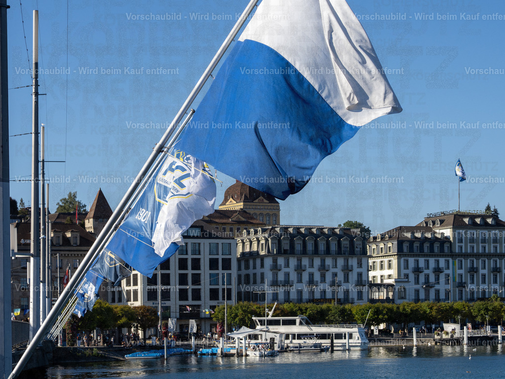 125 Jahre FCL – Luzern in Blau-Weiss | Die blau-weissen Fahnen wehen an der Seebrücke im Wind und zelebrieren das 125-Jahre-Jubiläum des FC Luzern. Dahinter erstreckt sich die Kulisse der Luzerner Seepromenade mit dem traditionsreichen Hotel Schweizerhof. - Realisiert mit Pictrs.com
