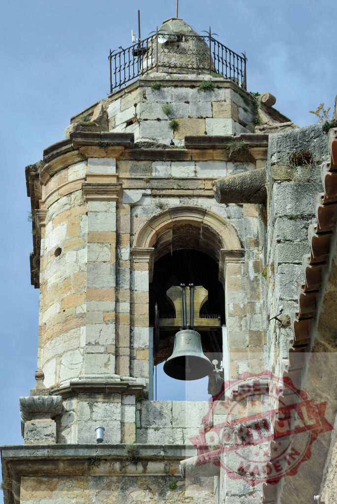 Historic stone bell tower with hanging church bell. Spain - Castellon | Ancient stone bell tower of a church with a metal bell against a clear sky - Realized with Pictrs.com