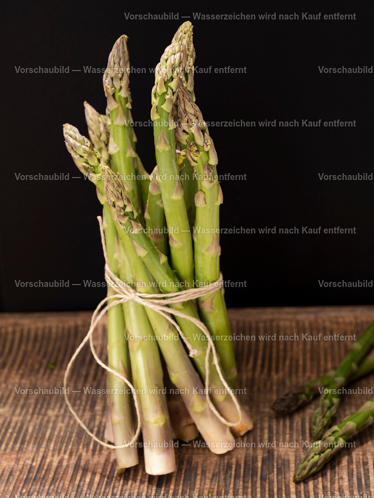 ein Bund frischer, grüner Spargel stehend auf alten Holzbrett | ein Bund frischer, grüner Spargel stehend auf alten Holzbrett - Realisiert mit Pictrs.com