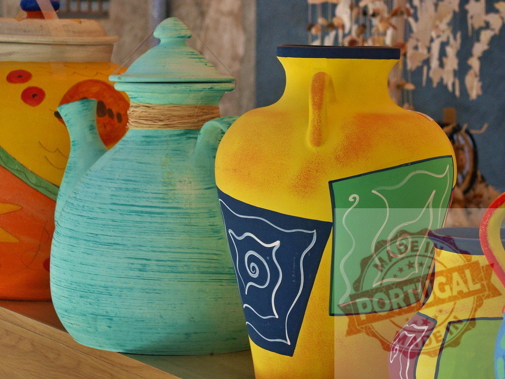 Hand painted ceramic pottery vases and pitchers displaying vibrant colors | Colorful artisan ceramics with abstract designs decorating an indoor shelf - Realized with Pictrs.com