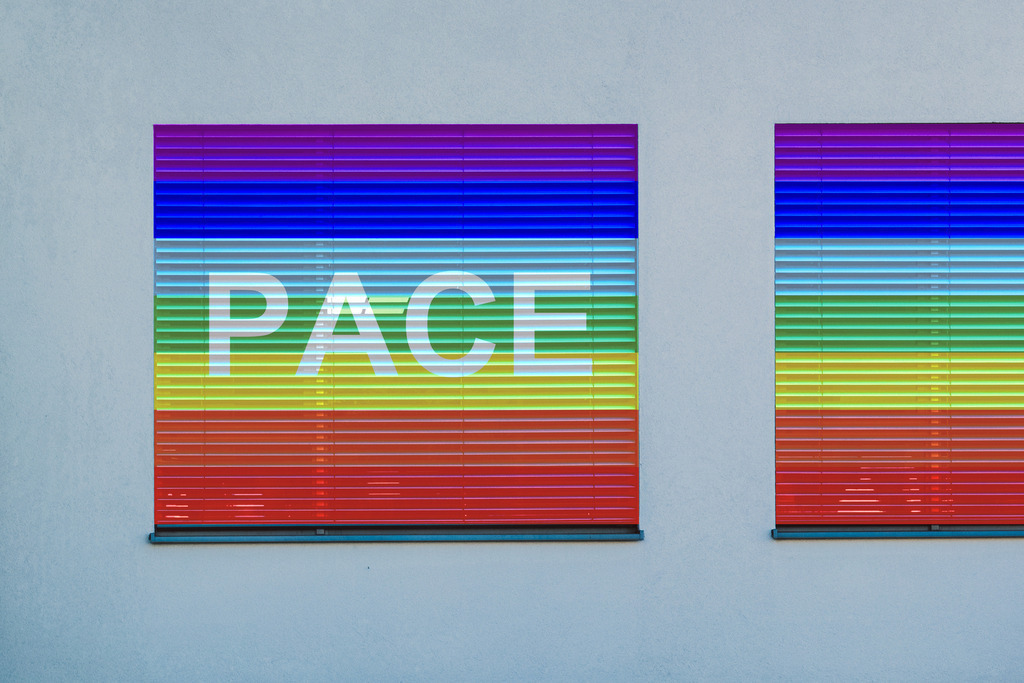 Pace Flagge auf Fenster Rolladen | Regenbogenfahne der Friedensbewegung („Pace-Flagge“) mit weißer Friedenstaube. Pace (lateinisch.) = Frieden.