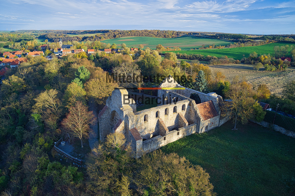 Walbeck_Oktober_0042 | Gern – passend im Stil der bisherigen Schlossgalerie:Die Aufnahme zeigt die Schlossruine Walbeck aus einer tiefen Drohnenperspektive. Kahle Bäume und die letzten goldbraunen Herbstblätter verleihen der historischen Anlage eine stimmungsvolle Atmosphäre, während sich im Hintergrund die sanft hügelige Landschaft des nördlichen Harzvorlandes erstreckt. Aus der niedrigen Flughöhe werden die erhaltenen Mauern, die architektonischen Strukturen und die Lage der Ruine besonders eindrucksvoll sichtbar.Das Schloss Walbeck geht auf eine mittelalterliche Burganlage zurück, die im Laufe der Jahrhunderte mehrfach erweitert und zu einem repräsentativen Schloss umgestaltet wurde. Nach wechselvoller Geschichte und mehreren Umbauten blieben Teile der Anlage als eindrucksvolle Ruine erhalten. Bis heute zeugen die mächtigen Mauerreste von der einstigen Bedeutung des Schlosses und prägen das Ortsbild von Walbeck.Die Drohnenaufnahme vermittelt einen außergewöhnlichen Blick auf die historische Schlossruine und ihre harmonische Einbettung in die herbstliche Landschaft. Das Zusammenspiel aus alter Bausubstanz, den kahlen Bäumen und den letzten Farbtupfern des Herbstes verleiht der Aufnahme einen besonderen Reiz und macht die Schlossruine Walbeck zu einem eindrucksvollen Zeugnis regionaler Bau- und Kulturgeschichte. - Realisiert mit Pictrs.com