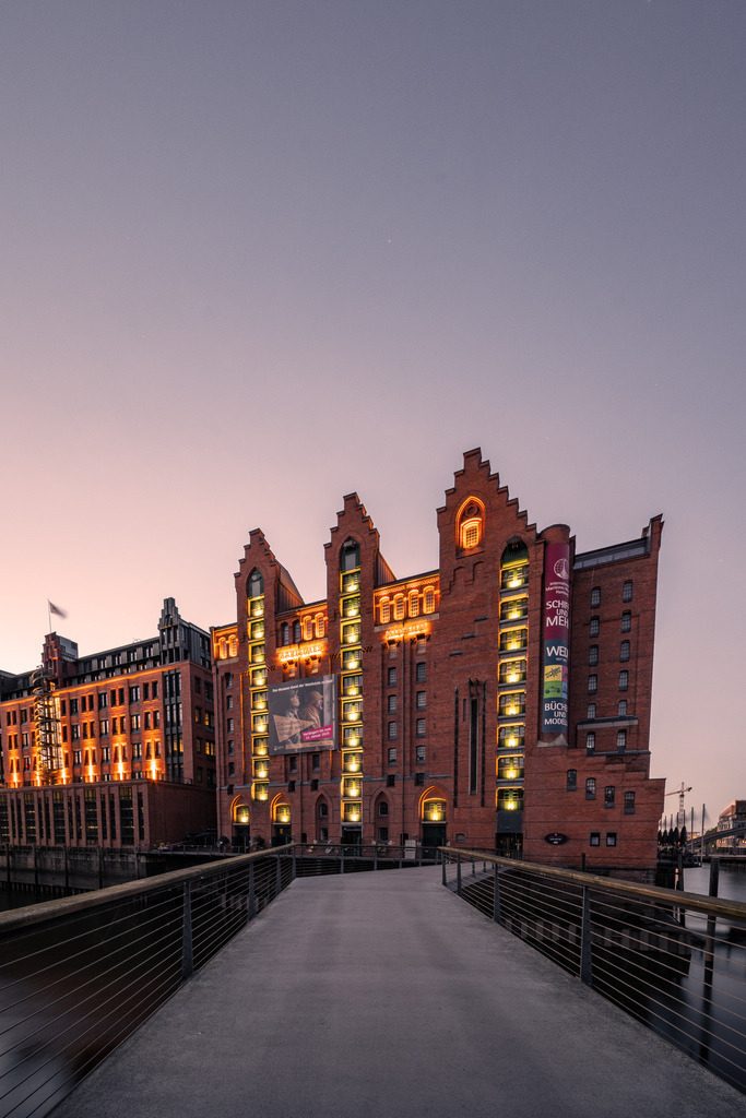 Historische Speicherstadt im Abendlicht | Die beleuchteten Backsteingebäude der Hamburger Speicherstadt entlang eines Fleets während der einsetzenden Abenddämmerung. - Realisiert mit Pictrs.com