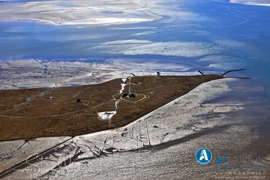 Luftbild Nordstrandischmoor, Lüttmoor, Bio­sphä­ren­re­ser­vat | Die Halligbahn Lüttmoorsiel–Nordstrandischmoor, auch Lorenbahn genannt, ist eine 1934 eröffnete Halligbahn in der Spurweite von 600 mm, die für den Transport von Baumaterial zur Befestigung der Hallig und der Lahnungen gebaut wurde. Diese Bahn ist eine nicht-öffentliche Bahnanlage im Eigentum des Landes Schleswig-Holstein und wird vom Landesbetrieb für Küstenschutz, Nationalpark und Meeresschutz Schleswig-Holstein (LKN-SH) betrieben.