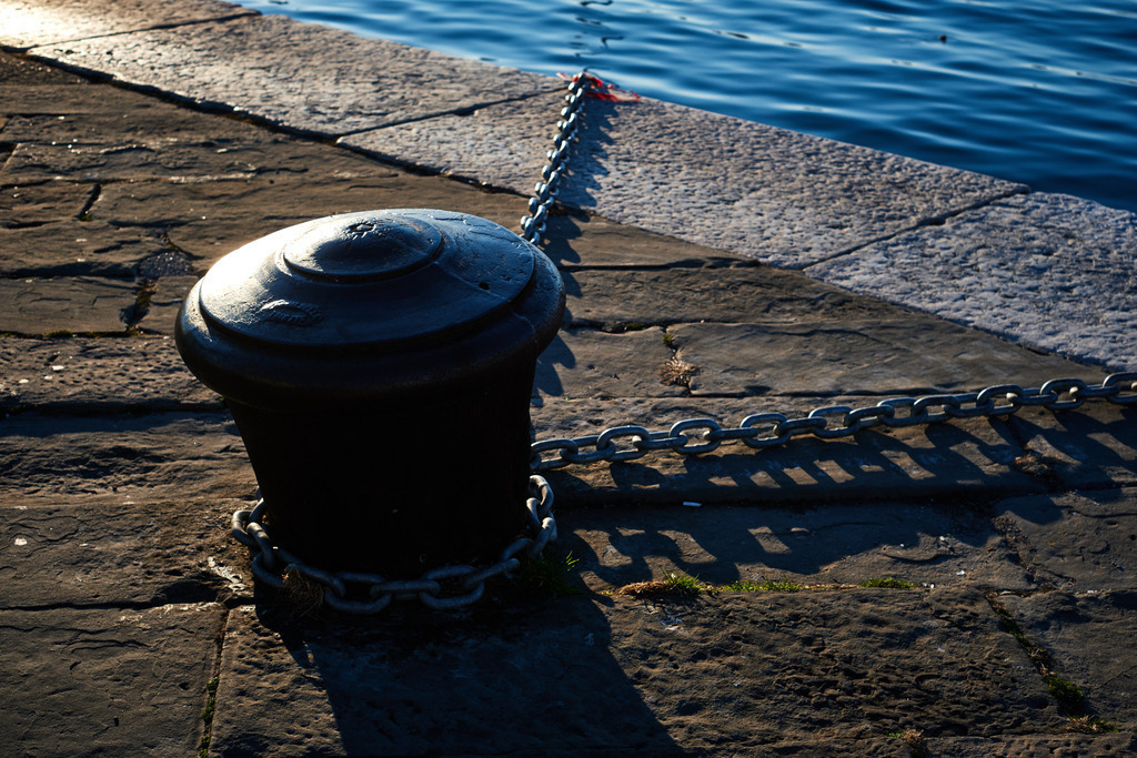 Poller mit Kette am Ufer | Triest, Austria - March 10, 2022: Poller mit Kette am Ufer. - Realisiert mit Pictrs.com