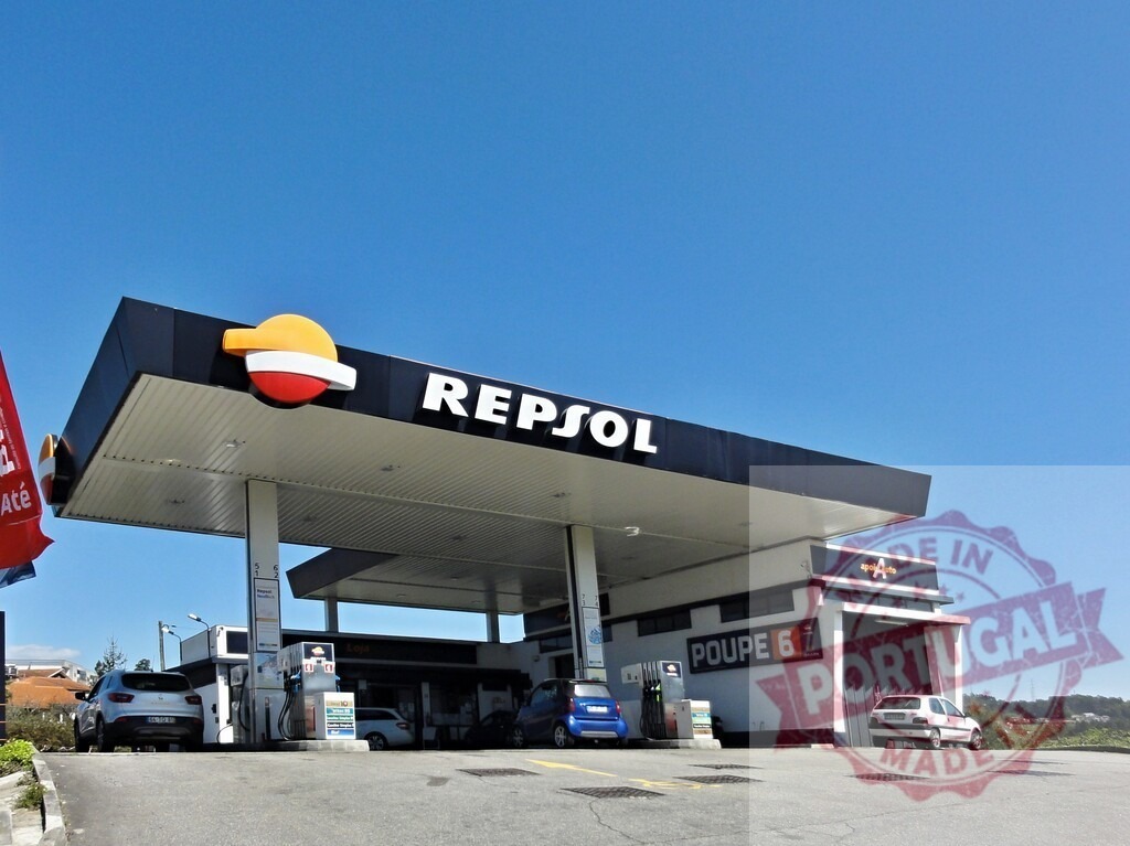 Repsol gas station with cars fueling under blue sky | Repsol gas station canopy and pumps with cars refueling, reflecting energy and transportation - Realisiert mit Pictrs.com