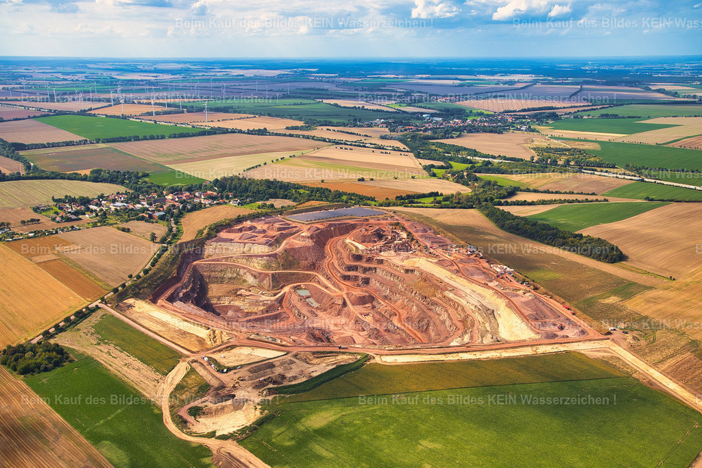 mammendorf_8857 | Blick aus dem tief fliegenden Tragschrauber auf den Steinbruch bei Mammendorf im Landkreis Börde. Das charakteristisch rosafarbene Gestein prägt die Abbauflächen und verleiht dem Motiv eine ungewöhnliche Farbwirkung.Die niedrige Perspektive bringt die Struktur des Steinbruchs und die verschiedenen Gesteinsschichten besonders deutlich zur Geltung. Gleichzeitig vermittelt die Aufnahme einen unmittelbaren Eindruck von der Dimension des Abbaugebietes.Das Luftbild dokumentiert einen industriell geprägten Rohstoffstandort und zeigt, wie sich auch ein funktionaler Steinbruch aus der Luft zu einem markanten Landschafts- und Industriemotiv entwickeln kann. - Realisiert mit Pictrs.com