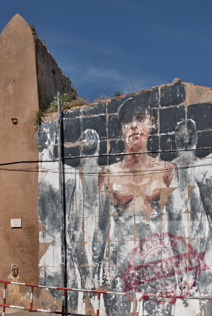 Large mural representing a person raising arms on a weathered wall | Large mural representing a person raising arms on a weathered wall in an urban setting, showcasing street art and adding a touch of artistic expression to the cityscape - Realisiert mit Pictrs.com
