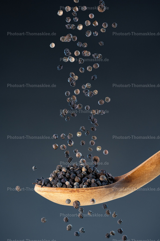 Schwarzer Pfeffer – Klassiker unter den Gewürzen | Schwarzer Pfeffer – Klassiker unter den Gewürzen. Kollektion: A spoon of tastefully seasonings.In dieser präzisen Studioaufnahme fallen zahlreiche ganze, aromatische schwarze Pfefferkörner von oben herab und landen auf einem rustikalen Holzlöffel. Durch die Verwendung von Highspeed-Blitzen wurde der Moment der Bewegung perfekt eingefroren, sodass jedes Korn in beeindruckender Schärfe sichtbar ist. Der Hintergrund ist ein sanfter, dunkler Blaugrauverlauf, der die warme, natürliche Struktur des Holzlöffels und die satte Farbigkeit der Pfefferkörner wirkungsvoll hervorhebt. Diese Szene vereint die Schönheit von Naturprodukten mit handwerklicher Fotokunst und eignet sich hervorragend als stilvolles Dekorationsmotiv sowohl im privaten als auch im gewerblichen Umfeld.Wo könnte man dieses Bild am besten aufhängen?Privater Bereich:In einer stilvollen Küche als kunstvolles Food-Highlight.Im Esszimmer als atmosphärischer Blickfang für Genießer.Gewerblicher Bereich:In Restaurants oder Bistros, die regionale oder internationale Küche anbieten.In Feinkostgeschäften oder Gewürzläden, um Authentizität und Qualität zu vermitteln.Alu-Dibond: Perfekte Wahl für moderne, minimalistische Räume – die matte Oberfläche betont die Details der Pfefferkörner und verleiht dem Motiv eine edle Tiefe.Acrylglas: Bringt die dunklen Kontraste und die glänzenden Körner besonders intensiv zur Geltung und schafft einen lebendigen 3D-Effekt.Poster: Eine flexible und kostengünstige Option, um Küchen, Cafés oder Delikatessengeschäfte stilvoll aufzuwerten.Leinwand: Auf einer strukturierten Leinwand wirken die natürlichen Materialien und die erdigen Farben besonders warm und harmonisch – ideal für gemütliche Räume. - Realisiert mit Pictrs.com