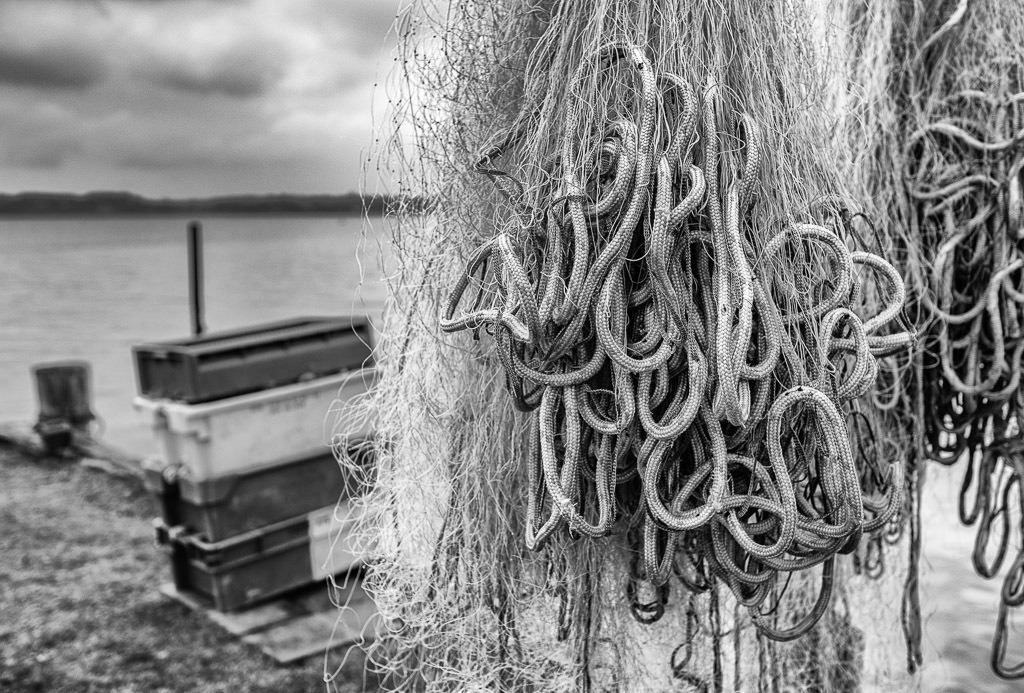 fischer-2020-020 | Die Landungsbrücken am Holmer Strand sind grasbewachsene Anleger der Schleswiger Fischer. Hier machen sie seit Jahrhunderten ihre Boote fest und lagern ihr Material wie diese Kisten und Netze. - Realisiert mit Pictrs.com