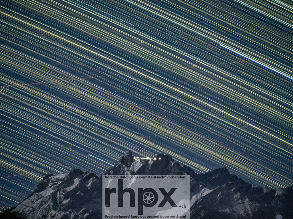 Startrails über dem Pilatus | Bewegung. Licht. Ewigkeit.Der Nachthimmel erwacht zum Leben, während unzählige Sterne ihre Bahnen über dem markanten Pilatusmassiv ziehen. Diese spektakuläre Langzeitbelichtung macht die Rotation der Erde sichtbar und setzt die Lichter der Bergstation in einen faszinierenden Kontrast zum dynamischen Sternenzelt.Wähle unter "Produktauswahl" dein Wunschformat: Vom klassischen Wandbild über Puzzle &amp; Tassen bis zum digitalen Download (z.B. als Handy-Hintergrund). - Realisiert mit Pictrs.com