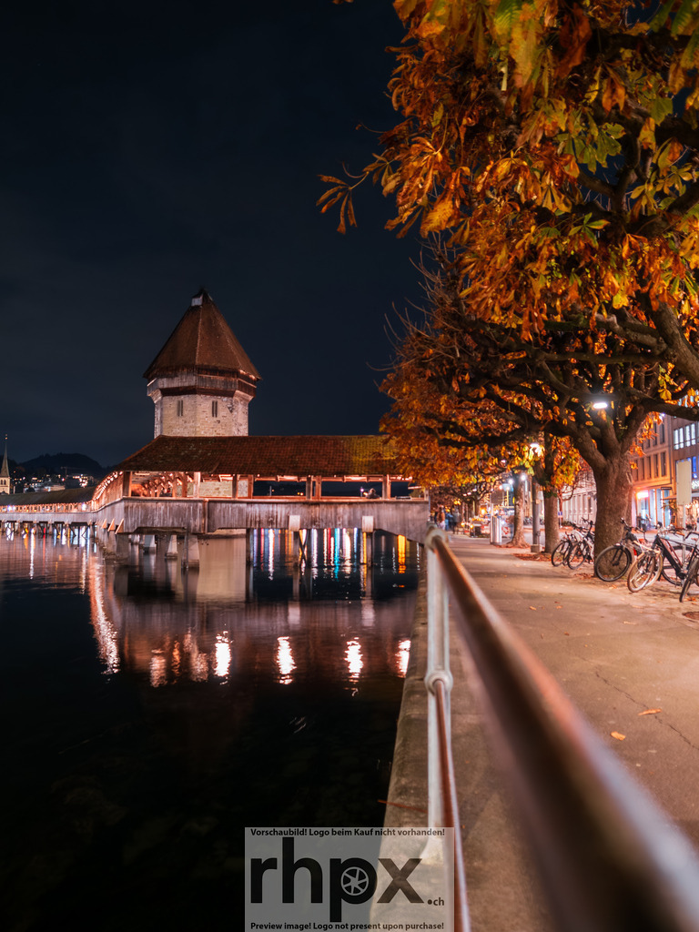 Herbstnacht in Luzern & Kapellbrücke | Herbstgold. Reuss. Stille.Die warmen Lichter der Altstadt spiegeln sich in der dunklen Reuss und vertreiben die Kühle der Herbstnacht. Eine goldene Atmosphäre umhüllt die historische Kapellbrücke in dieser klaren Jahreszeit.Wähle unter "Produktauswahl" dein Wunschformat: Vom klassischen Wandbild über Puzzle &amp; Tassen bis zum digitalen Download (z.B. als Handy-Hintergrund). - Realisiert mit Pictrs.com