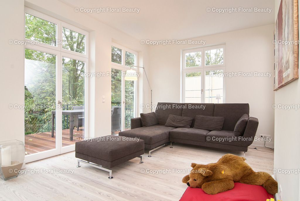 Modernes Wohnzimmer mit braunem Sofa | Braunes Sofa im Wohnzimmer mit großem Teddybären im Vordergrund. Terrasse - Realisiert mit Pictrs.com