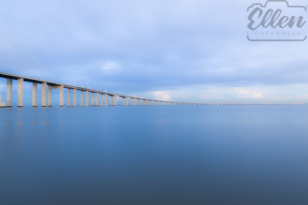 Whispers of the Horizon | Soft hues of blue and grey meet in perfect harmony, where the bridge stretches endlessly across tranquil waters. A moment of pure stillness — where structure and nature dissolve into serenity. - Realisiert mit Pictrs.com