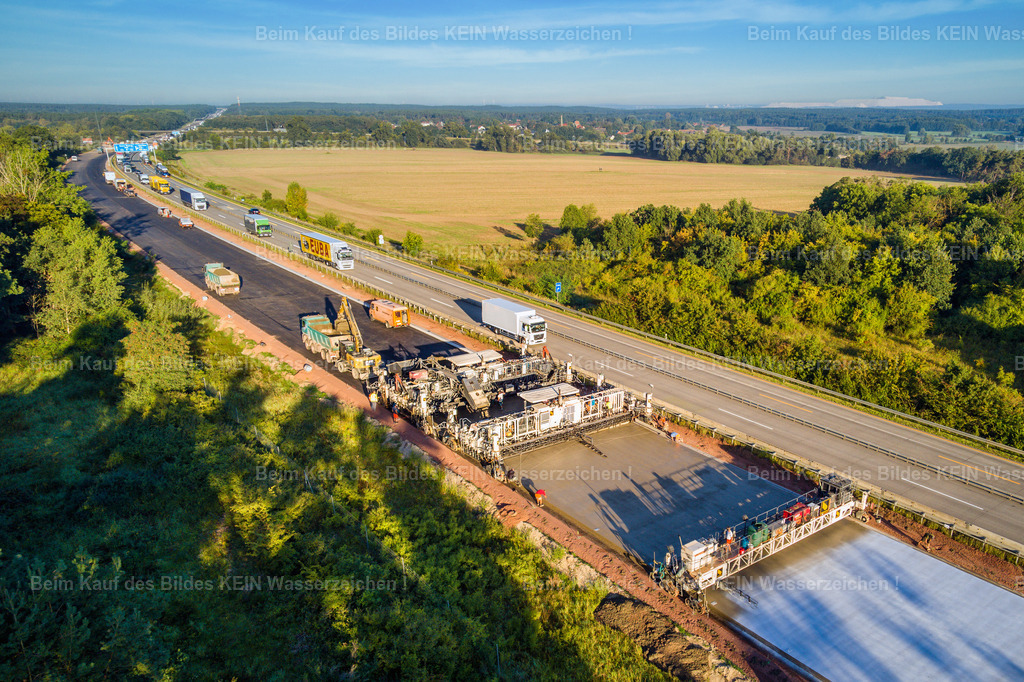 Mammendorf Andesit Baustelle A2-0010 | Blick aus der tief fliegenden Drohne auf eine Autobahnbaustelle während der Erneuerung der Fahrbahn. Die Aufnahme entstand im Rahmen einer Baustellendokumentation und zeigt die laufenden Arbeiten aus unmittelbarer Nähe.Besonders interessant ist das Zusammenspiel von Baustelle und fließendem Verkehr: Während auf einem Teil der Autobahn die neue Fahrbahn entsteht, läuft der Verkehr auf den angrenzenden Fahrspuren weiter.Die niedrige Drohnenperspektive macht Maschinen, Fahrbahnflächen, Absperrungen und den laufenden Verkehr besonders anschaulich. Gleichzeitig vermittelt das Bild einen realistischen Eindruck von den Bedingungen, unter denen eine solche Baumaßnahme bei laufendem Autobahnbetrieb durchgeführt wird.Ein Beispiel für die professionelle fotografische Begleitung von Infrastruktur- und Straßenbauprojekten – dokumentarisch, nah am Geschehen und aus einer Perspektive, die vom Boden aus nur schwer möglich wäre. - Realisiert mit Pictrs.com