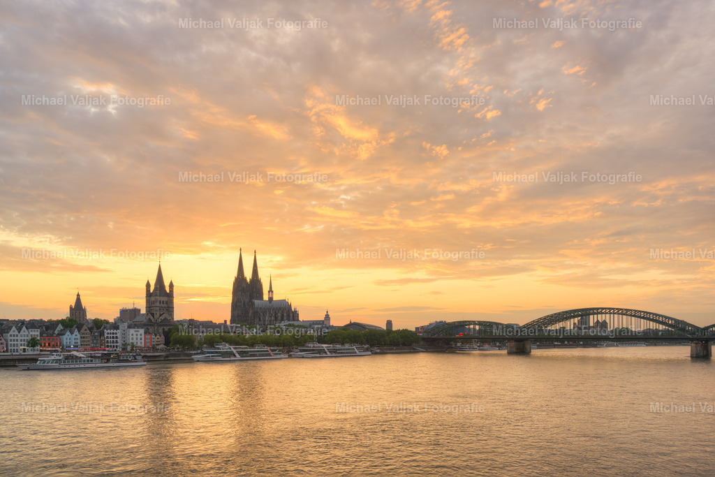 Die Skyline von Köln bei Sonnenuntergang | Die Skyline von Köln ist ein atemberaubender Anblick, besonders wenn sie im warmen Licht des Sonnenuntergangs erstrahlt. Die Silhouetten der Gebäude, darunter der berühmte Kölner Dom, zeichnen sich scharf gegen den farbenfrohen Himmel ab. Dieses Schauspiel der Natur betont die einzigartige Architektur der Stadt und schafft einen Moment der Ruhe und Schönheit, der sowohl Einheimische als auch Besucher immer wieder verzaubert. - Realisiert mit Pictrs.com